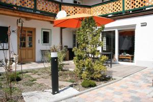 une maison avec un parasol orange sur une terrasse dans l'établissement Ferienwohnungen Rosenhof, à Tegernsee
