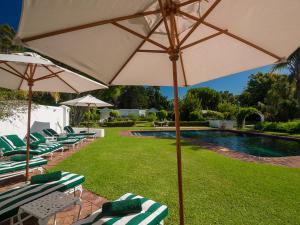 a group of lawn chairs with an umbrella next to a pool at St. James of Knysna in Knysna