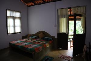 ein Schlafzimmer mit einem Bett in einem Zimmer mit Fenstern in der Unterkunft Silver Hill Ecovillage in Kurunegala