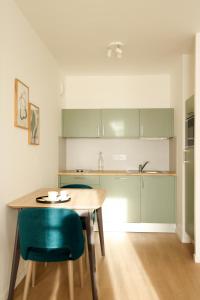 una cocina con armarios verdes y una mesa y sillas de madera. en Résidence services seniors CAZAM Pontoise, en Pontoise