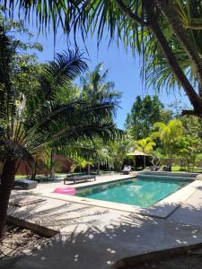 - une piscine bordée de palmiers dans une cour dans l'établissement The Barefoot Blondie Village, à Gili Air