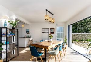 a dining room with a wooden table and blue chairs at MAISON NEUVE LUMINEUSE AU CALME PROCHE DES PLAGEs in Quiberon