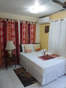 1 dormitorio con 1 cama blanca grande y cortinas rojas en 11 Glenhope Avenue en Kingston
