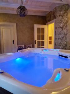 eine große Badewanne mit blauer Beleuchtung in einem Zimmer in der Unterkunft Krupówka Resort Boutique Hotel Szczyrk - Baseny, SPA, Wellness, Restauracja z widokiem in Szczyrk