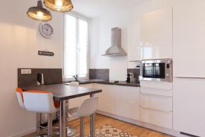 a kitchen with white cabinets and a table and chairs at Downtown Cannes short walk to beaches the Croisette the Palais in Cannes