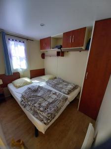 een kleine kamer met 2 bedden en een raam bij Mobil-home camping 