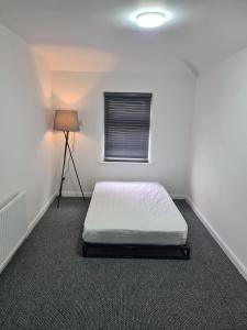 a white room with a bed and a lamp at Emergency - Bedrooms Only in Birkenhead