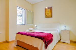 Un dormitorio con una cama con una manta roja. en Apartamentos Ribera del Puerto, en El Puerto de Santa María