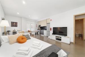 a white bedroom with a large bed and a television at LUMO Apartment Fátima in Fátima