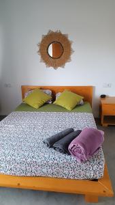 uma cama com almofadas e um espelho na parede em BEM VINDOS A KASA em Porto Novo