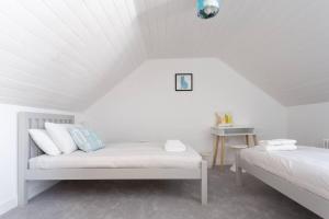a white room with two beds and a table at Sandpiper Cottage By The Sea. Broadstairs. in Kent