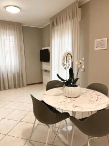 a dining room with a table with chairs and flowers on it at Residenza Mediterranea Apartments in Rimini