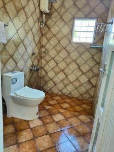 a bathroom with a toilet and a tiled floor at Kurialacherry House Alleppey in Ambalapulai