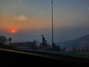 una vista de una ciudad con la puesta de sol en el fondo en Neora Backpackers Hostel en Darjeeling