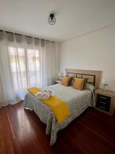 1 dormitorio con 1 cama con manta amarilla en Piso céntrico a 10 min de la playa con garaje incluido, en Castro Urdiales