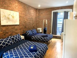 a bedroom with two beds and a brick wall at NYC Empire Apartments in New York