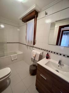 a bathroom with a sink and a tub and a toilet at Piso céntrico a 10 min de la playa con garaje incluido in Castro-Urdiales