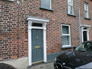a blue door on a brick building with a car at Stunning 3 Bedroom townhouse in the heart of city in Belfast
