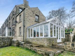 an old stone house with a conservatory in front of it at Bagshaw Mews in Bakewell