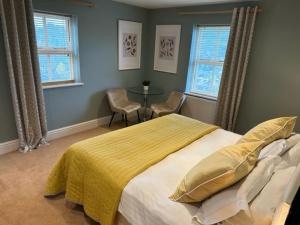 a bedroom with a bed and a table and windows at Bagshaw Mews in Bakewell