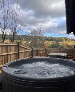a hot tub on a deck with a wooden fence at Countryside 3 Bedroom Log Cabin With Private Hot Tub - Ash in Leominster