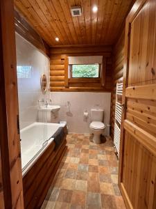 a bathroom with a tub and a toilet and a sink at Countryside 3 Bedroom Log Cabin With Private Hot Tub - Ash in Leominster