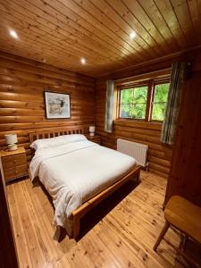 a bedroom with a bed in a wooden cabin at Countryside 3 Bedroom Log Cabin With Private Hot Tub - Ash in Leominster