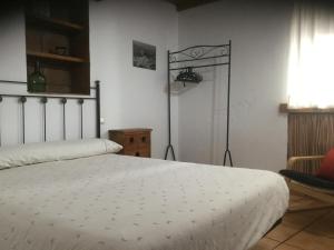 1 dormitorio con 1 cama blanca y 1 silla en Las Casitas de mi Abuela, en Casares