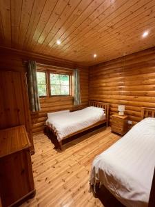 a room with two beds in a log cabin at Countryside 3 Bedroom Log Cabin With Private Hot Tub - Ash in Leominster
