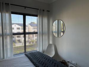 1 dormitorio con cama, espejo y ventana en Luxury one bedroom apartment en Somerset West