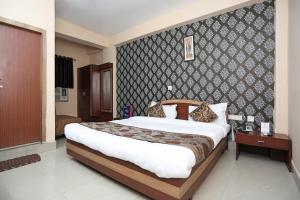 een slaapkamer met een groot bed en een muur bij Collection O Hotel Greenpark in Jamshedpur