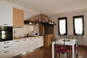 een keuken met witte kasten en een tafel met stoelen bij Maison Younesco - Villa indipendente exclusive in Castagnole Lanze