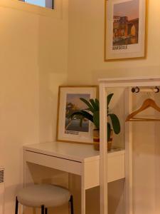 einen weißen Schreibtisch mit einer Pflanze und einem Bild in der Unterkunft Maï Homes - Le Cœur Canebière in Marseille