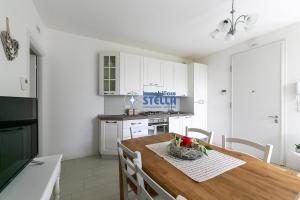 cocina blanca con mesa de madera y sillas en Villa Stella, en Lido di Jesolo