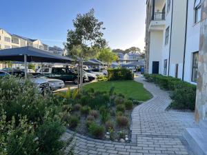 a walkway next to a parking lot with cars parked at Luxury one bedroom apartment in Somerset West