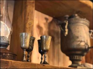 three wine glasses sitting on a shelf with vases at Zubyria Lodge in Krekhayev