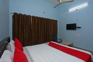 a bedroom with a red and white bed and a ceiling fan at OYO The Ambience in Bhubaneshwar