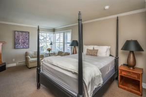 ein Schlafzimmer mit einem Himmelbett und einem Stuhl in der Unterkunft Cannon Beach Hotel Collection in Cannon Beach