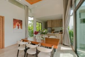 a dining room with a wooden table and white chairs at Bliss Villa at Shambhala Grand in Bang Tao Beach