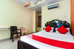 - une chambre avec un grand lit et des oreillers rouges dans l'établissement OYO Sindhura Guest House, à Raspari Palao