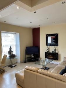 a living room with a couch and a television at The Penthouse at Ty Gwyn in Llandudno