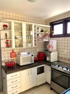 una cocina con armarios blancos y electrodomésticos blancos en Casa em condomínio, beira mar e piscina Barra de São Miguel - Maceió- AL en Barra de São Miguel