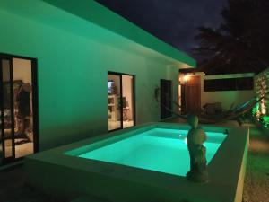 a swimming pool in a house with green lighting at Casa Flamingo Telchac in Telchac Puerto