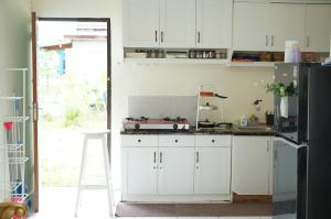 cocina con armarios blancos y nevera negra en Casadova Homestay, en Tumbangrungan