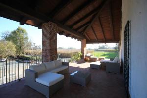 een patio met witte banken en tafels en een hek bij Il Vecchio Mulino Di Bairo in Baglio