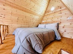 uma cama num quarto de madeira num chalé de madeira em Alex's House Shirokë em Shkodër