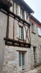 an old stone building with white windows on it at Maison paisible avec parking in Montpezat-de-Quercy