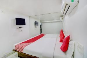 OYO Hotel Blue Light Near Gateway Of India Mumbai في مومباي: غرفة نوم بسرير ومخدات حمراء وتلفزيون