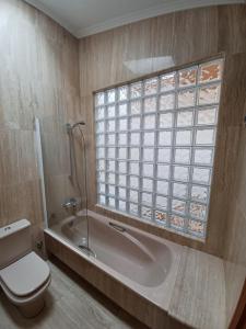 baño con bañera, aseo y ventana en Ático48 en Redondela