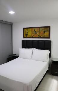 1 dormitorio con cama blanca y cabecero negro en Moblat MED, en Medellín